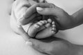 Female hands of young mother holding her newborn baby feet, closeup image with blur baby in background Royalty Free Stock Photo