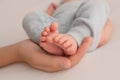 Female hands of young mother holding her newborn baby feet, closeup image with blur baby in background Royalty Free Stock Photo