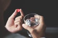 Female handsis holding red pill in heart shape and glass of water Royalty Free Stock Photo