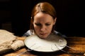 Female head on a plate on a dark background. Fear of diet, apathy concept