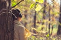 Female in headphones standing near big maple tree in park and listen sounds or music in the autumn forest. Concept. Indian summer