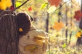 Female in headphones standing near big maple tree in park and listen sounds or music in the autumn forest. Concept. Indian summer