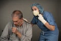 Female healthcare employee listening to male patient chest with a stethoscope in worry. Royalty Free Stock Photo