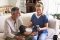 Female healthcare worker making home visit to a senior man taking blood pressure Royalty Free Stock Photo