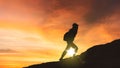 Female hiker climbing a hill at sunset time