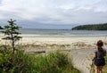 A female hiker exploring the sandy beaches of nels bight and experimental bight, surrounded by forest and the pacific ocean