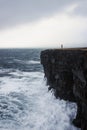 Female hiker in pink jacket on Hafnaberg lava sea cliff in Hafnir Reykjanes Southern Peninsula Reykjanesskagi Iceland