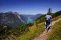 Female hiker hiking on a trail on the hills overlooking a beautiful lake surrounded by mountains