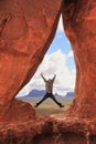 Female hiker jumping inside Teardrop Arch in Southern Utah