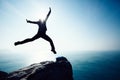 Female hiker jumping on sunrise seaside cliff edge Royalty Free Stock Photo