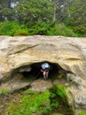 A female hiker just entering into a small dark sea cave along the rocky shore of the west coast trail
