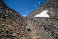 A female hiker makes her way down a dangerous hiking path of loose rocks