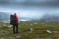 Female hiker overlooking Rapa river valley in rough arctic landscape of Sarek National Park, Sweden, on a very cloudy