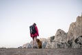 Female hiker in pink jacket standing on top of a mountain with her dog Royalty Free Stock Photo