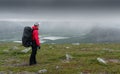 Female hiker in red jacket with heavy backpack overlooking Rapa river valley in arctic landscape of Sarek National Park Royalty Free Stock Photo