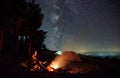 Female hiker sitting near campfire under night starry sky. Royalty Free Stock Photo