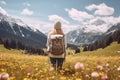 Female hiker standing in flowering alpine meadow and admiring a scenic view from a mountain top. Adventurous young girl with a