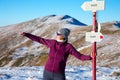 Female Hiker staying at Path Sign and admiring scenic View in Winter Mountains Royalty Free Stock Photo