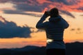 Female hiker taking pictures of beautiful sunset sky with smartphone