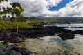 Female Hiker and Tide Pool On The Volcanic Shoreline of Keiki Beach Royalty Free Stock Photo