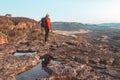 Female hiker at to the top of a rugged cliff face overlooking a valley