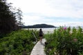 A female hiker walking along the boardwalk to nels bight surrounded by forest and the pacific ocean Royalty Free Stock Photo