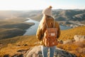 Female hiker wearing casual clothes admiring a scenic view from a mountain top. Adventurous young girl with a backpack. Hiking and