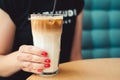 Female hipster with cold latte in modern cafe. Coffee break. Coffee latte with ice. Woman nails with red manicure. Female manicure