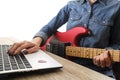 Casually dressed young woman with guitar playing songs in the room at home. Laptop on table. Online guitar lessons concept. Male g Royalty Free Stock Photo