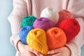 Female holding colorful or multicolored wool yarns on blue background. Many multi-colored balls of threads close-up. Needlework or Royalty Free Stock Photo