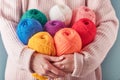 Female holding colorful or multicolored wool yarns on blue background. Many multi-colored balls of threads close-up. Needlework or Royalty Free Stock Photo