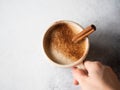 Female holding cup of cappuccino coffee with spices - anise star and cinnamon stick on grey background Royalty Free Stock Photo