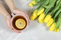 Female holding cup of tea and yellow tulips.