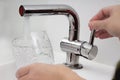 Female holding glass at water tap and filling water with lead contamination Royalty Free Stock Photo