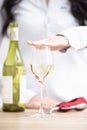 Female holding a hand above the glass of white wine with bottle and wine opener next to it Royalty Free Stock Photo