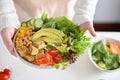 A female holding a plate of Buddha bowl or plant based salad vegetables mixed. close-up image