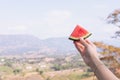 A female holding a watermelon slice in front of the mountain