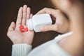 Female holding a white pill bottle and red pills in heart shape. Royalty Free Stock Photo