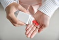 Female holding a white pill bottle and red pills in heart shape. Royalty Free Stock Photo