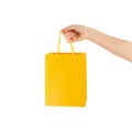 Female holds in hand yellow clear empty blank craft paper gift bag for purchases after shopping isolated on white background with Royalty Free Stock Photo