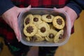 Female home baker holds up a plastic storage container filled with traditional Christmas peanut butter kisses cookies