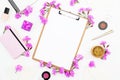 Female homework space with clipboard, notebook, pink flowers and accessories on white background. Flat lay Royalty Free Stock Photo