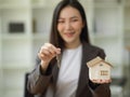 Female house realtor or real estate agent holding house keys chain and house model Royalty Free Stock Photo