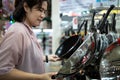 Female housewife or cook choosing teflon frying pan or deciding to buy steel frying pan for cooking in her kitchen,asian woman