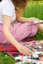 Female human hand holding brush and reaching out to oil color palette, woman artist painting process outdoor in the park Royalty Free Stock Photo