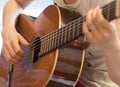 Female human hand playing an accoustic guitar strumming the strings