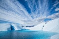 Ice climber standing above massive ice cave flooded with deep blue water from the melting Matanuska Glacier in Alaska