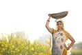 Female Indian farmer carrying iron pan on head in agriculture field