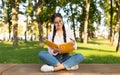 Female indian student girl writing notes to notebook while sitting on bench in university campus or park Royalty Free Stock Photo