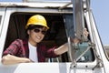 Female industrial worker adjusting mirror while sitting in logging truck Royalty Free Stock Photo